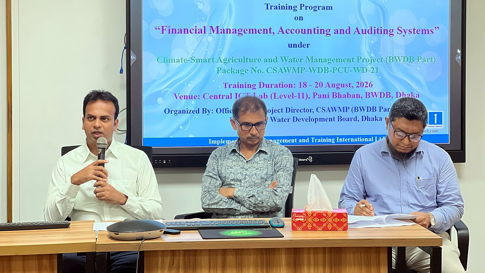 Officials on the dais in front of the Financial Management, Accounting and Auditing Systems training banner at the Central ICT Lab, Pani Bhaban
