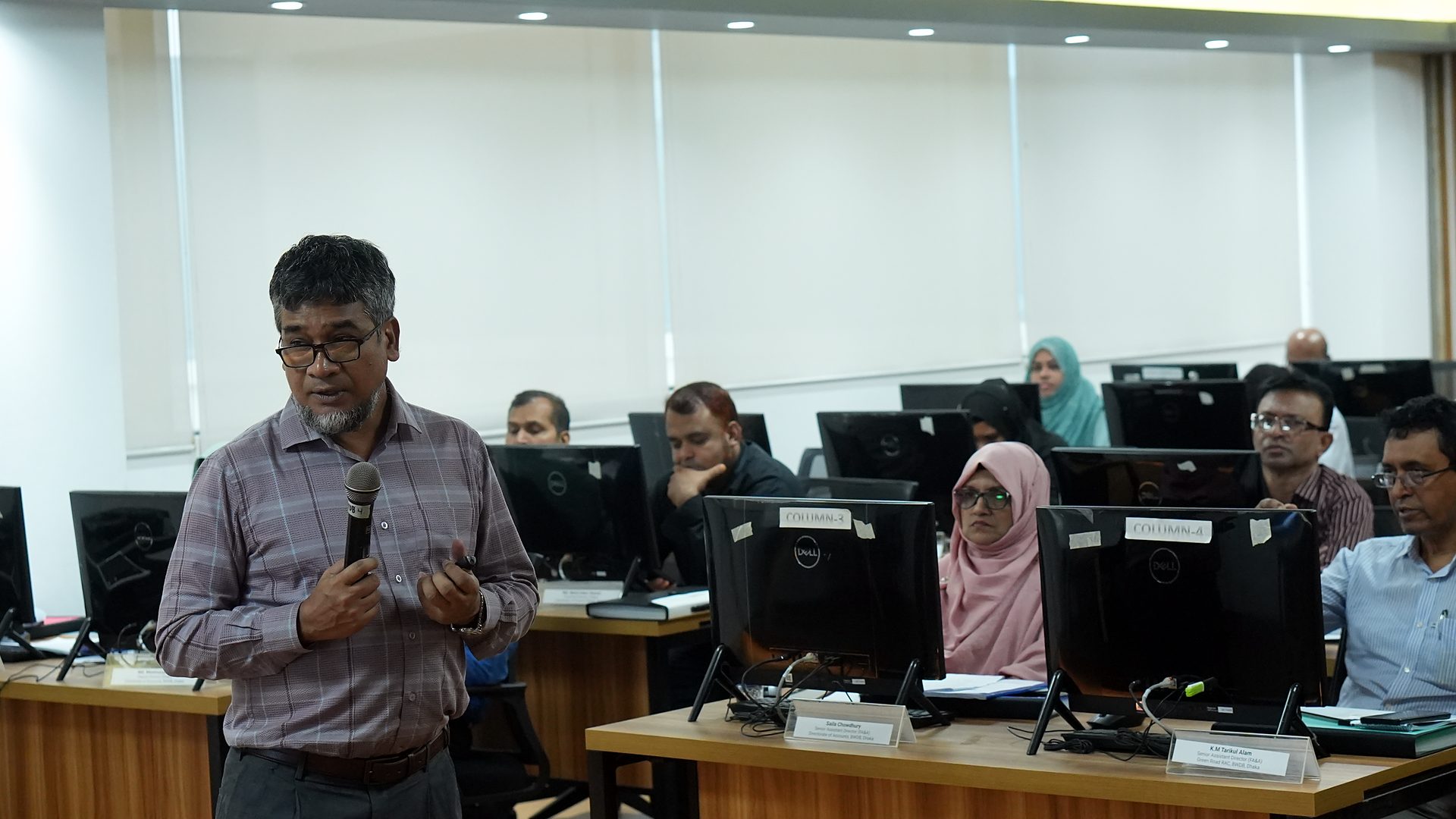 Participant speaking with a microphone among the workstations