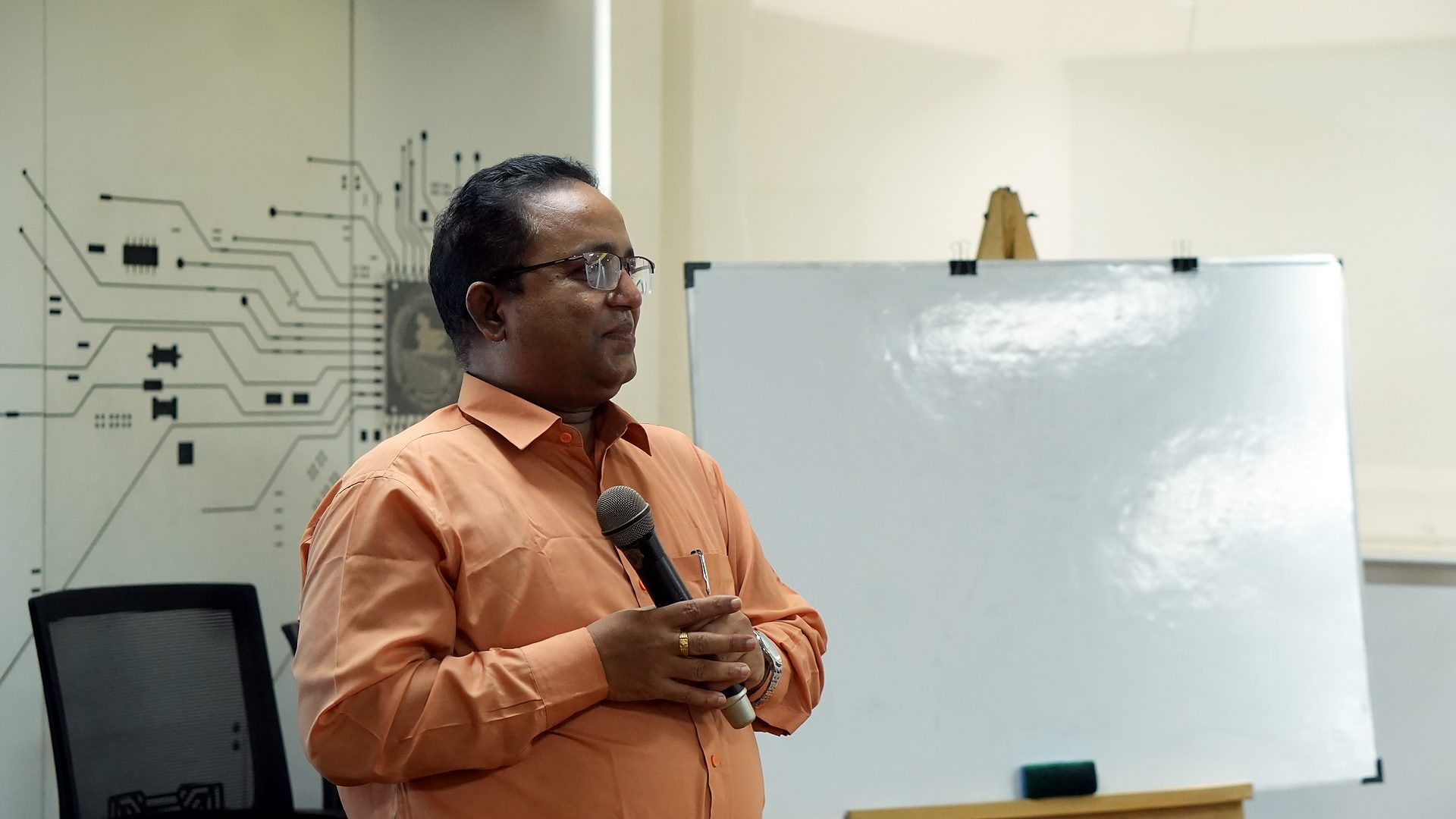 Resource person speaking beside a whiteboard in the Central ICT Lab