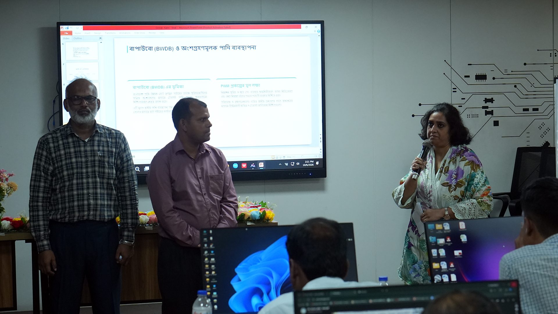 Team member presenting with a microphone beside a Bangla slide