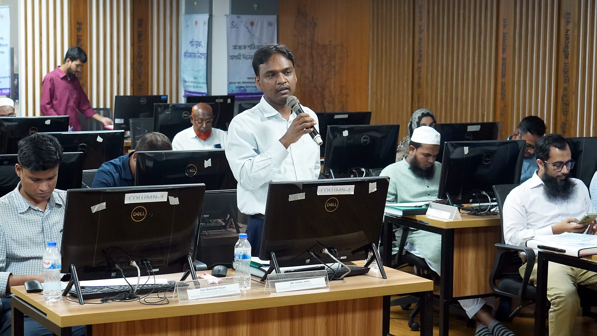 Participant standing to speak with a microphone among the workstations
