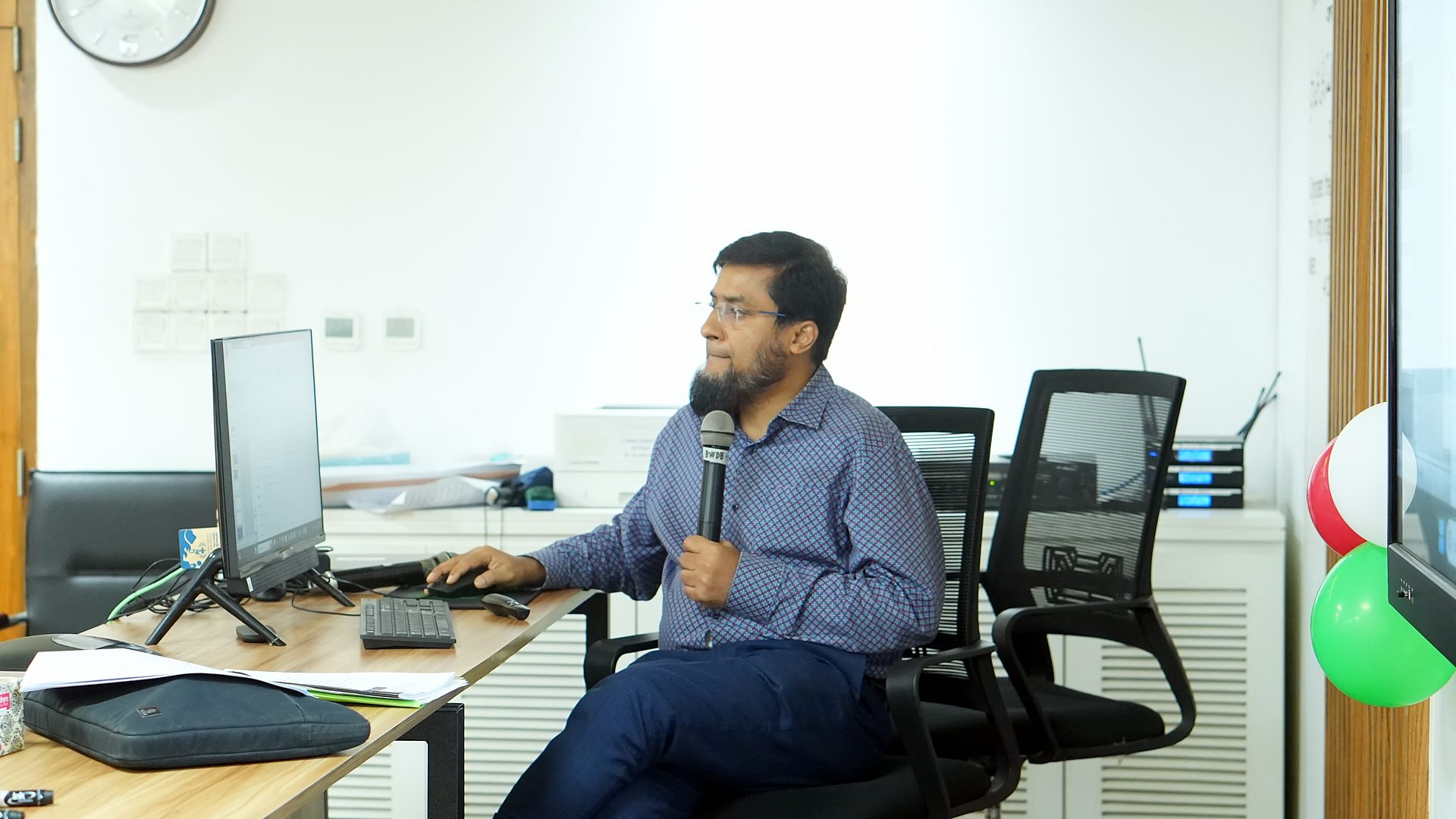 Resource person seated at a workstation with a microphone