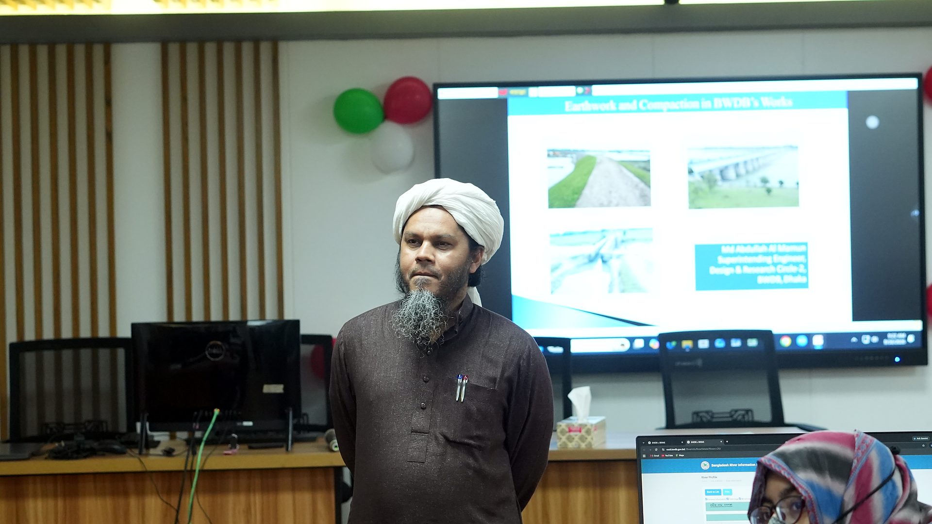 Resource person beside slides of hydraulic structures on the lab screen