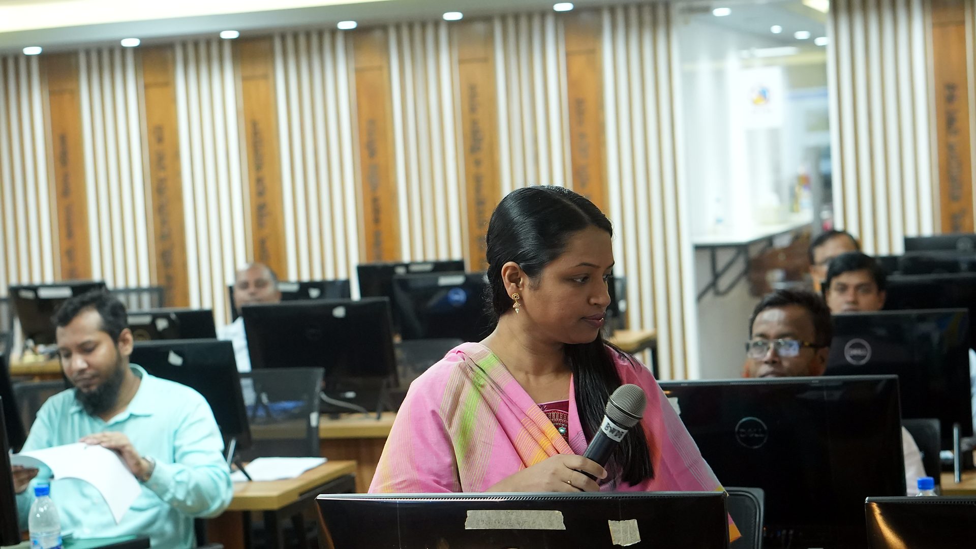Participant speaking with a microphone at her workstation