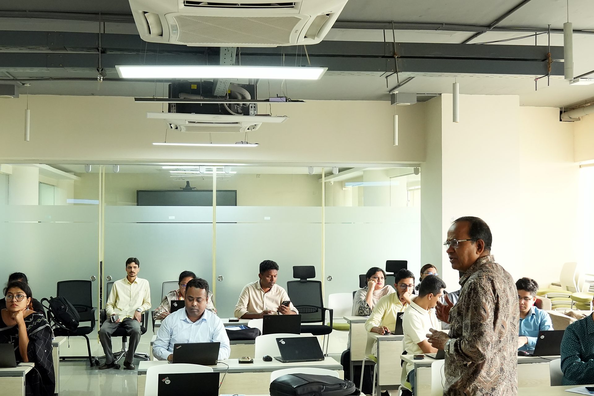 Wide view of the PMP Day 2 session at a2i, ICT Tower, with the trainer addressing the 46-member cohort