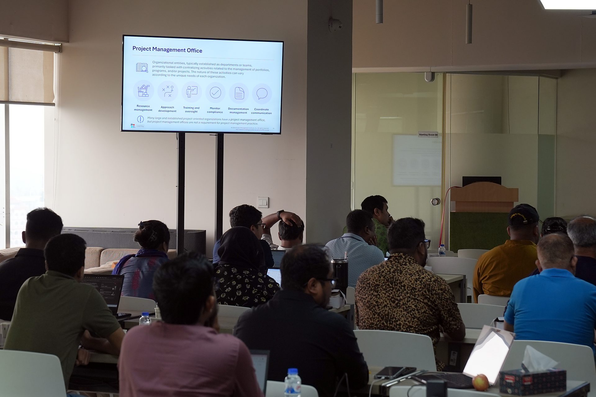 Project Management Office slide on screen with participants in the foreground