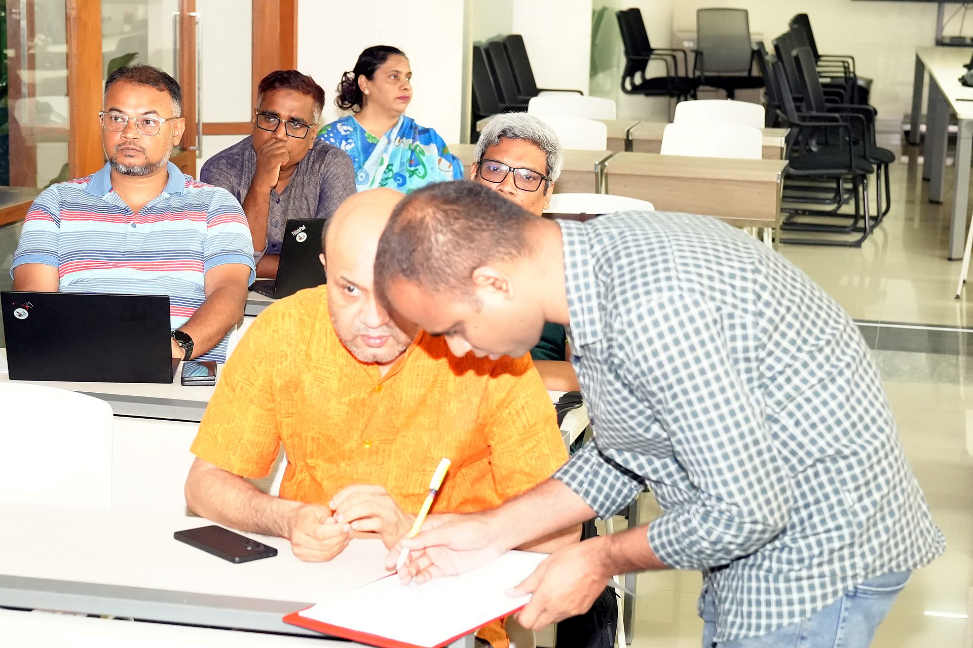A participant signing the attendance sheet with an MTI Ltd. team member