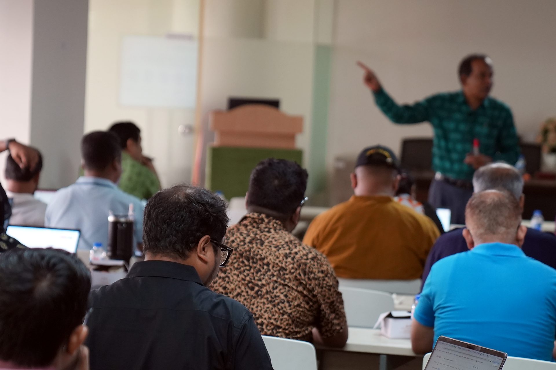Trainer pointing toward the screen while addressing participants