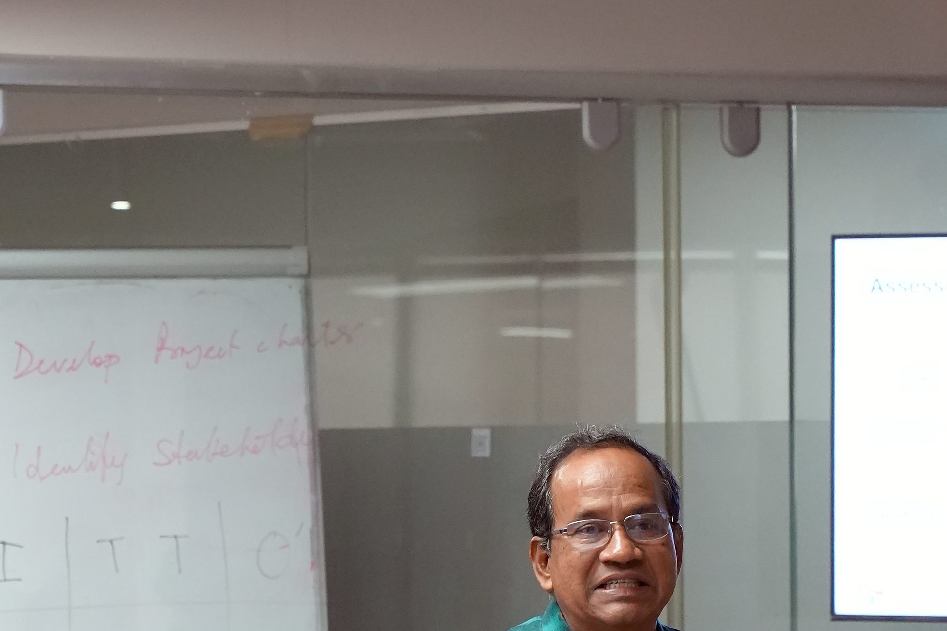Trainer in front of a whiteboard listing Develop Project Charter and Identify Stakeholders