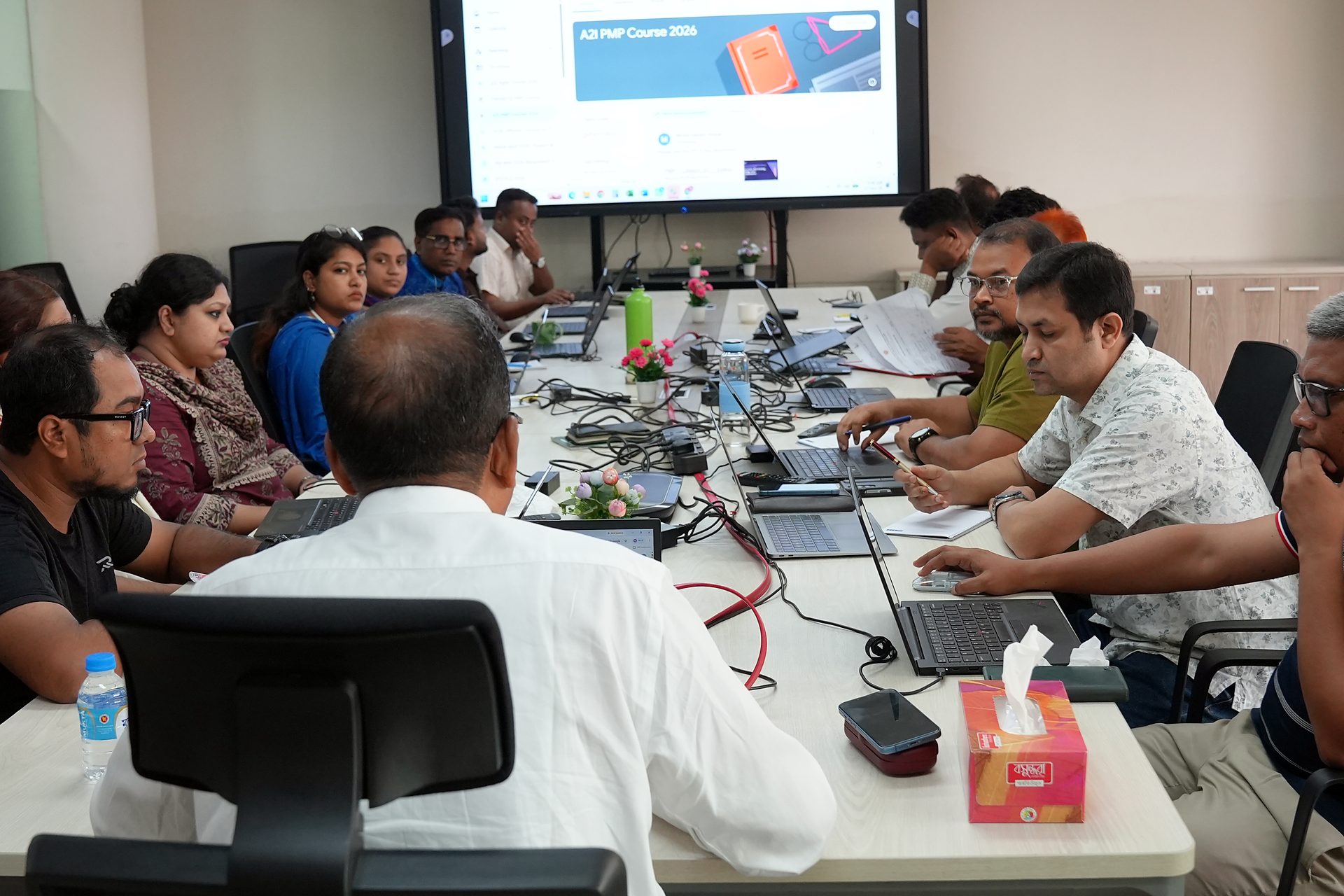Wide view of the boardroom with the course on screen