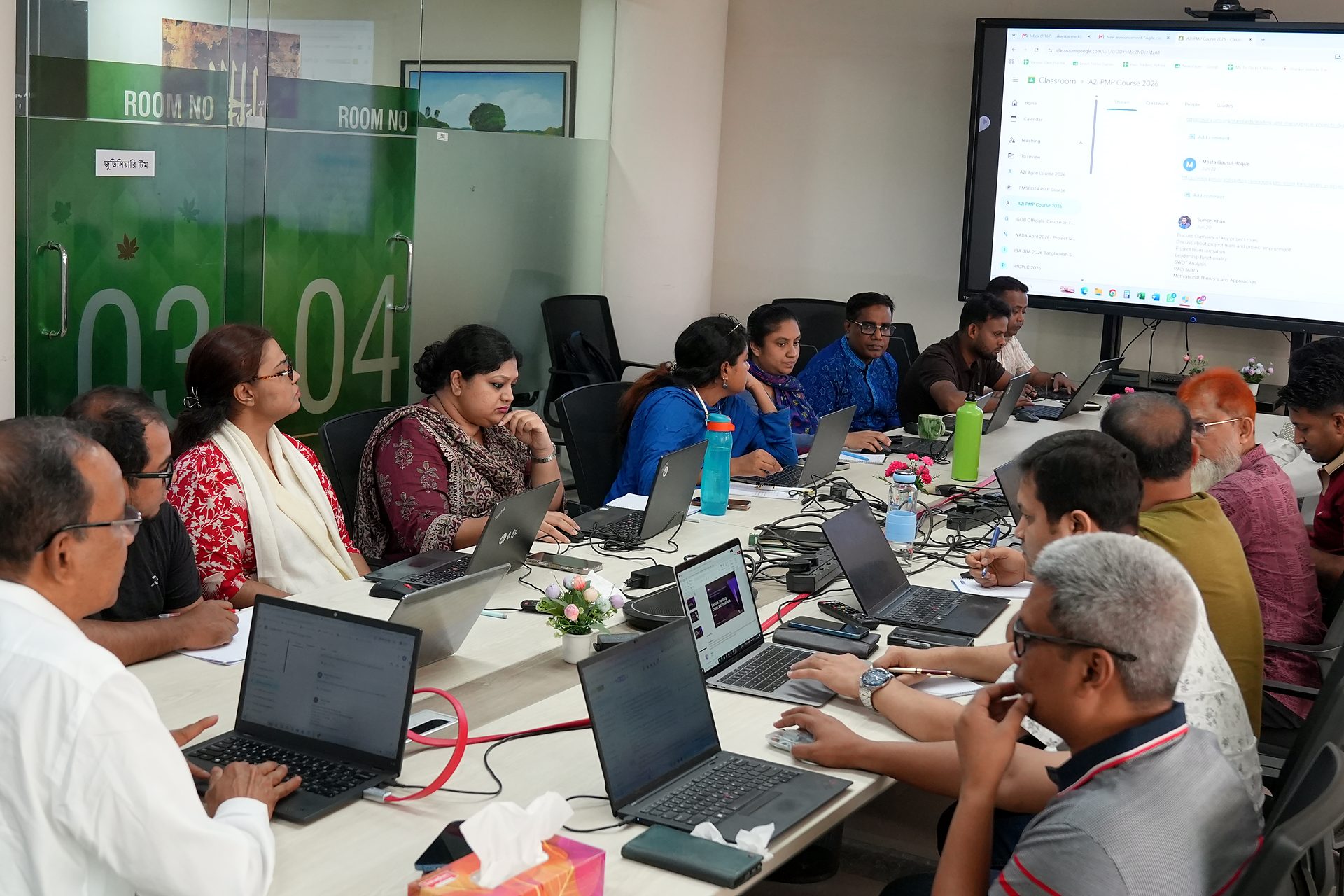 Participants working at the boardroom table with the course on screen