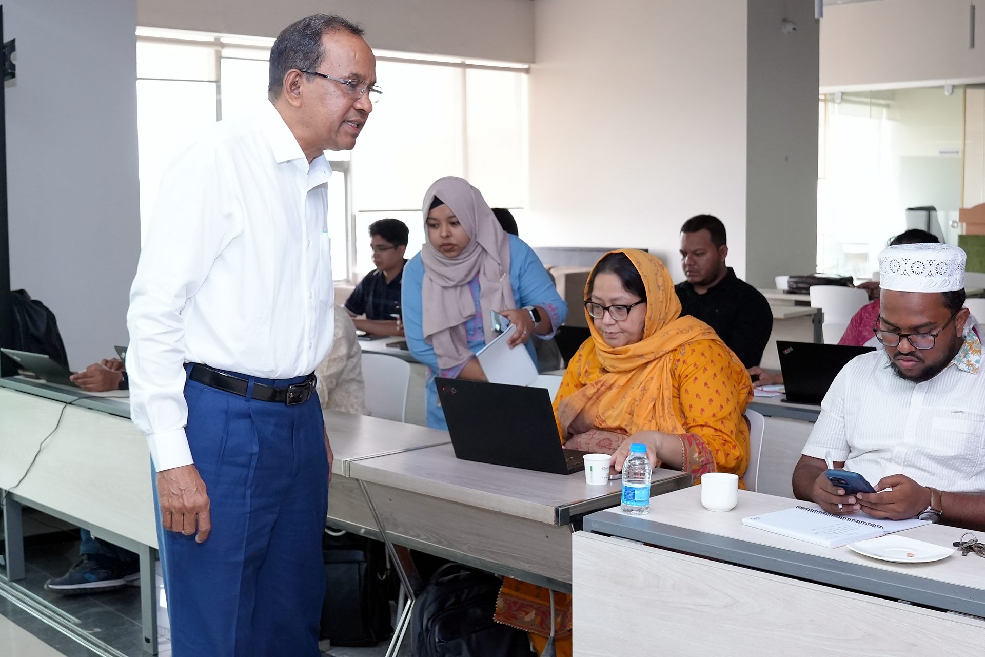 Trainer standing beside participants working at laptops