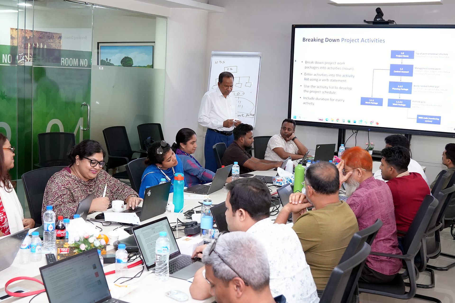 Trainer beside the Breaking Down Project Activities slide showing work packages and activities